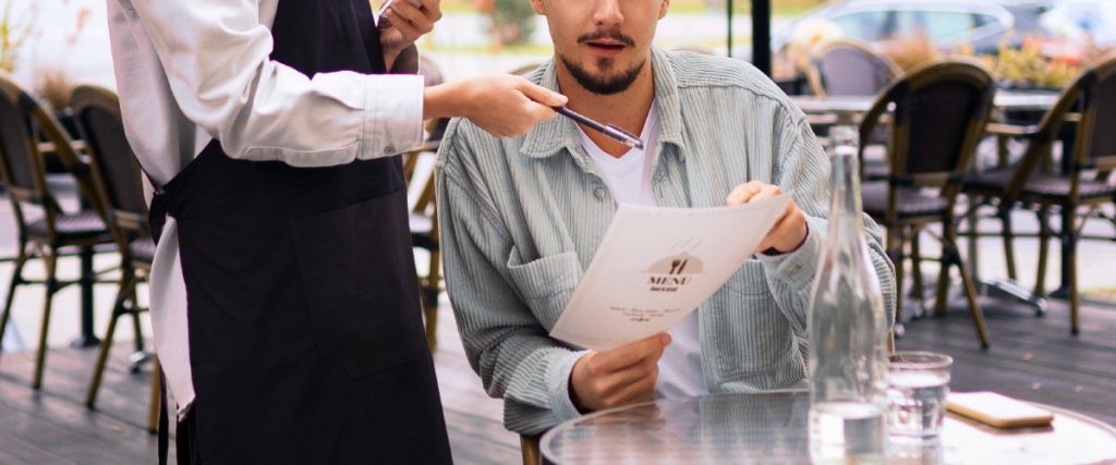 Moza mostrando el menú a un cliente en un restaurante como parte de la experiencia del cliente